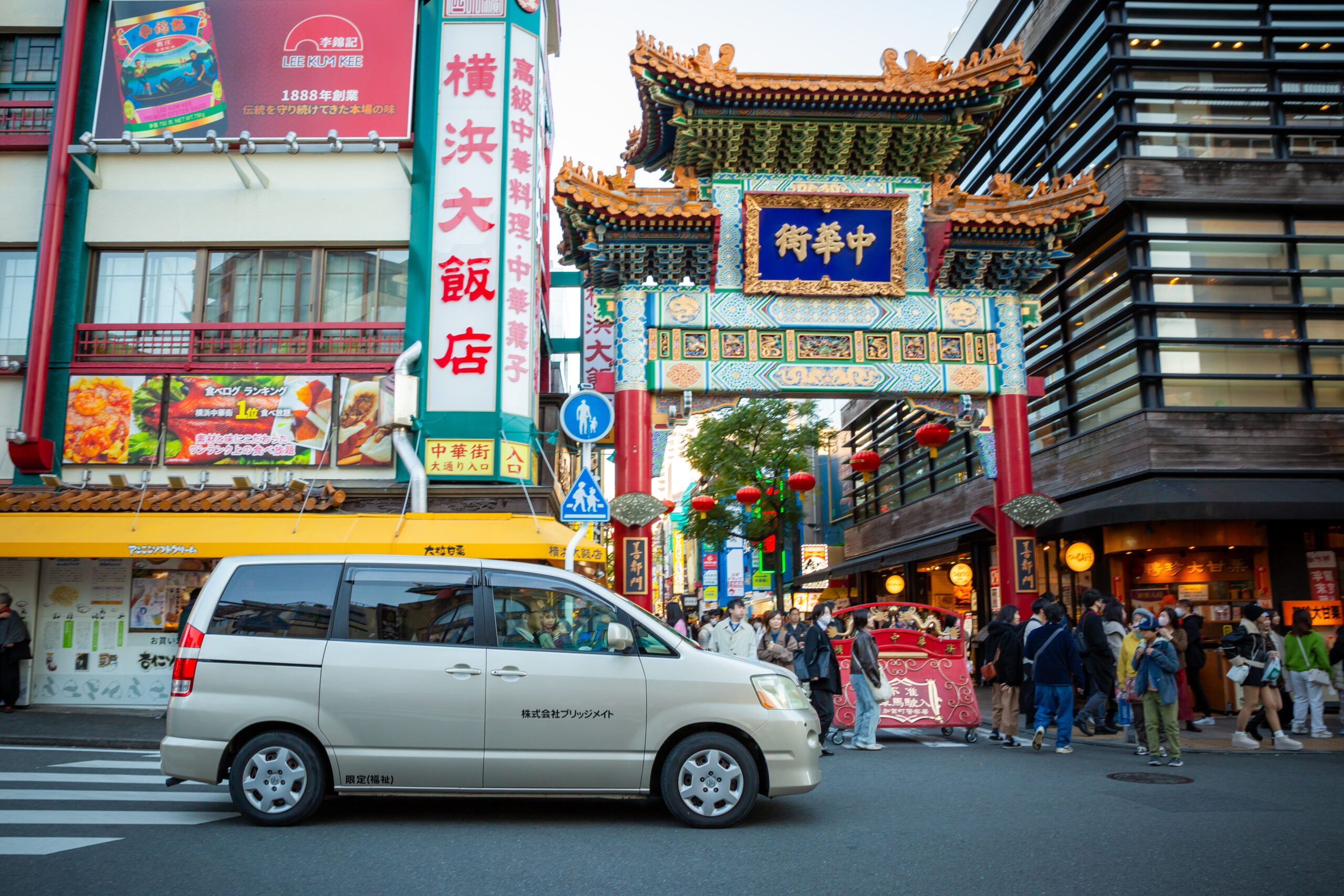 横浜中華街の善隣門の前を通過する介護タクシー車両