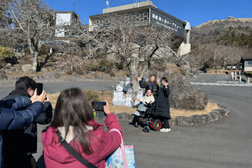 IMG_7773-2 - 株式会社ブリッジメイト 箱根駒ヶ岳ロープウェイ駅の前で記念写真を撮る訪日外国人旅行者