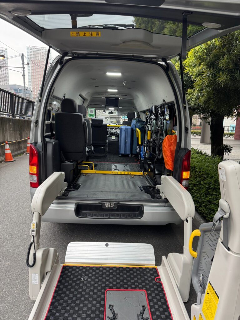 Back of a wheelchair-accessible van with the ramp deployed and a spacious interior for mobility devices, seating along the left and luggage on the right
