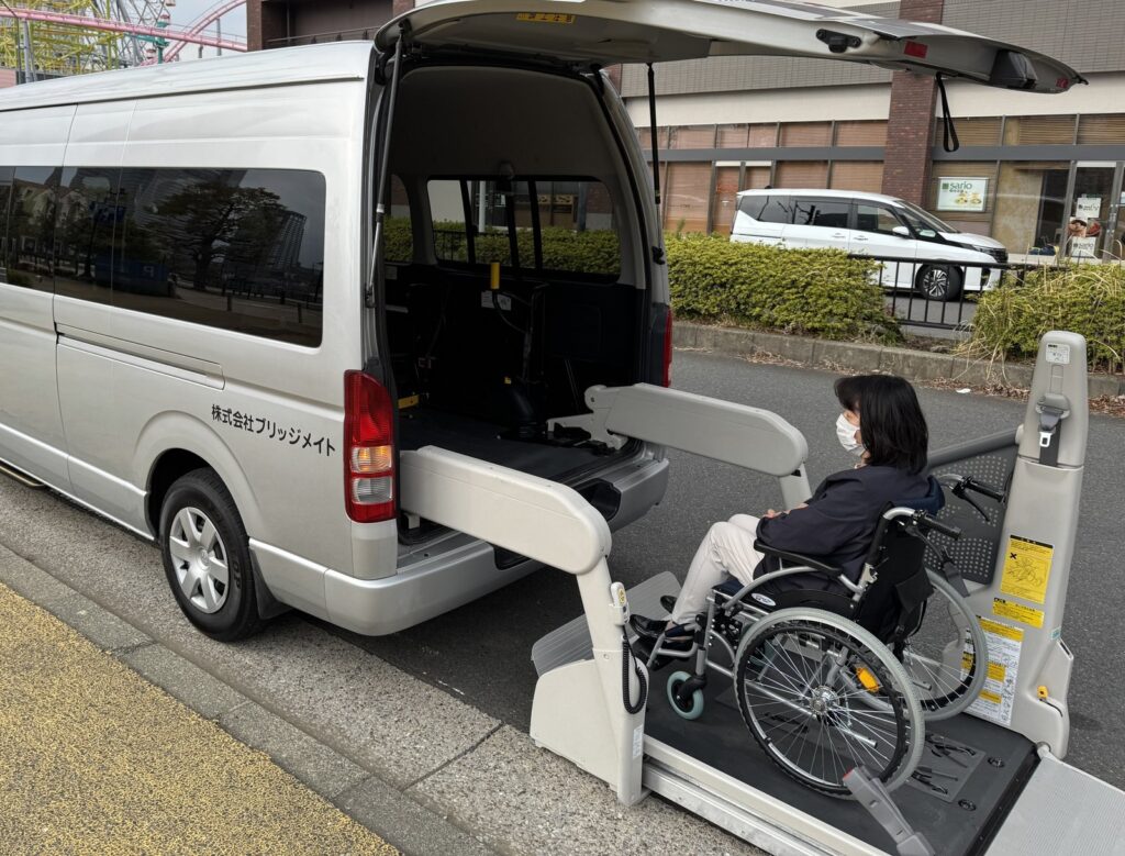 Passenger boarding our Toyota HiAce via the rear wheelchair lift on a Yokohama street